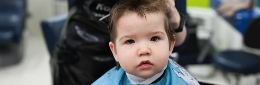 bébé qui se fait couper les cheveux par un coiffeur