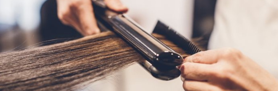 coiffeuse qui lisse les cheveux de sa cliente