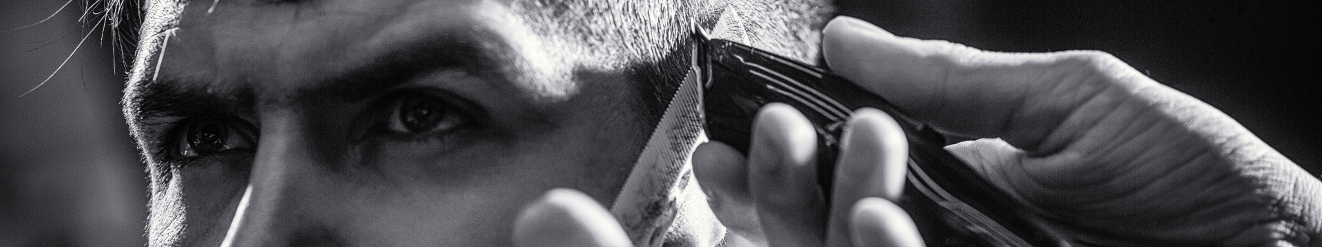 Coiffeur qui fait un dégradé avec une tondeuse à son client